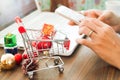 Online payment, Close up at gift boxes in shopping cart and Christmas decoration, woman hands using smartphone and laptop computer Royalty Free Stock Photo