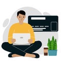 Online payment concept. Close up of a large credit card. A man sits cross-legged, holding a laptop in his hand. Royalty Free Stock Photo