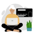 Online payment concept. Close up of a large credit card. An old woman sits cross-legged, holding a laptop in his hand. Royalty Free Stock Photo