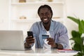 Online Payments. Smiling Black Male Freelancer Using Smartphone And Credit Card Royalty Free Stock Photo