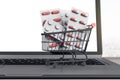 Online pharmacy concept with pills in shopping cart on black laptop keyboard