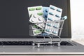 Online pharmacy medicine concept with pills in shopping cart on laptop keyboard