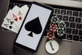 Online poker casino theme. Gambling chips, smartphone and playing cards on laptop keyboard Royalty Free Stock Photo