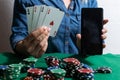 online poker player with a smartphone at a casino table with cards and chips. Royalty Free Stock Photo