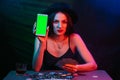 online poker player with a smartphone at a casino table with cards and chips Royalty Free Stock Photo