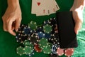 online poker player with a smartphone at a casino table with cards and chips. Royalty Free Stock Photo