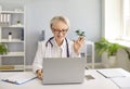 Online practitioner video calling her patient and waving hello at laptop computer Royalty Free Stock Photo