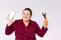 Online promotion concept. Smiling woman holding a repair tool and a phone with a white screen in hand to talk about the