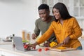 Online Recipe. Joyful black couple using laptop computer in kitchen while cooking Royalty Free Stock Photo