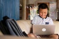 Online remote learning, distance education and homeschooling concepts. School kid Asian preteen boy in headphone using laptop Royalty Free Stock Photo