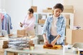 Online shop manager in shirt folding yellow sweater on desk before packing