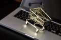 Online shopping bank card nearby a laptop and mini shopping cart Royalty Free Stock Photo