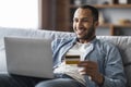 Online Shopping. Cheerful Handsome Black Man Using Laptop And Credit Card Royalty Free Stock Photo