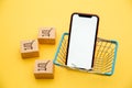 Online shopping concept. Boxes, basket and smartphone isolated on yellow background