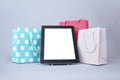 Online shopping concept. Close-up tablet mockup with white screen with bright gift bags on gray background