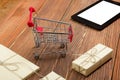 Online shopping concept - Empty Shopping Cart, laptop and tablet pc, gift box on rustic wooden background Royalty Free Stock Photo