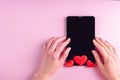 Online shopping concept. Female hands on a black blank tablet screen with red heart shape on a pink background Royalty Free Stock Photo