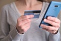 Female holding credit card while using her smart phone for inputting card information and making payment Royalty Free Stock Photo