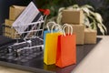 Online shopping concept. little shopping cart, boxes, colorful bags, bank card, dollars stand on laptop Royalty Free Stock Photo