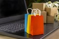 Online shopping concept. little shopping cart, boxes, colorful bags, bank card, dollars stand on laptop Royalty Free Stock Photo