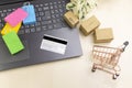 Online shopping concept. little shopping cart, boxes, colorful bags, bank card, dollars stand on laptop Royalty Free Stock Photo