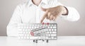 Online shopping concept. Man pointing on empty Shopping cart with keyboard on background Royalty Free Stock Photo