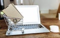 Online shopping concept with miniature shopping cart and laptop computer on table Royalty Free Stock Photo