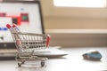 Concept of online shopping: Little shopping cart and a laptop in the blurry background Royalty Free Stock Photo