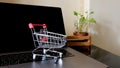 Online shopping concept. Shopping cart, laptop on the desk. Royalty Free Stock Photo