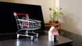 Online shopping concept. Shopping cart, laptop on the desk. Royalty Free Stock Photo