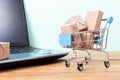 Online shopping concept. Shopping cart, small boxes, laptop and credit card on the desk