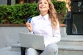 Online shopping concept. Young blonde woman holding a credit card and doing online payment with laptop outdoors Royalty Free Stock Photo