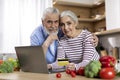 Online Shopping. Elderly Spouses Posing With Laptop And Credit Card In Kitchen Royalty Free Stock Photo