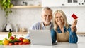 Online Shopping. Elderly Spouses Posing With Laptop And Credit Card In Kitchen Royalty Free Stock Photo