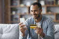 Online Shopping. Handsome Black Man Using Smartphone And Credit Card At Home Royalty Free Stock Photo