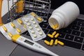 Online shopping with home delivery. Trolley with pills on laptop keyboard and medical tools
