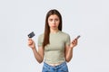 Online shopping, home lifestyle and people concept. Upset silly pouting woman showing empty credit card and mobile phone
