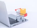 Online shopping. Mini shop cart trolley with colorful paper bags over a laptop computer on white table background, buying at home Royalty Free Stock Photo