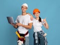 Online Shopping For Repair. Couple In Hardhats Holding Laptop Showing Thumb Up Royalty Free Stock Photo