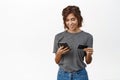 Online shopping. Smiling young woman using mobile phone and credit card to pay, make purchase, order or register in web Royalty Free Stock Photo