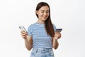 Online shopping. Young woman paying with credit card and mobile phone, smiling and looking relaxed, purchase smth in Royalty Free Stock Photo