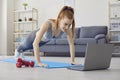 Online sport exercises at home. Workout at home. Redhead girl doing exercises at home.