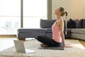 Online sport fitness yoga training. young woman doing exercises with opposite laptop. training at home