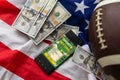 Online sports betting. Dollars are falling on the background of a hand with a smartphone and a soccer ball. Creative Royalty Free Stock Photo