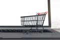 Online store business concept with blank white laptop monitor and black trolley store. Mockup