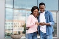 Online Taxi App. Happy Black Couple Standing Near Airport Terminal With Smartphone