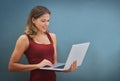 Online and in touch. Shot of a young woman holding a laptop against a gray background. Royalty Free Stock Photo