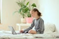 Online training. Additional activities at home. Smiling beautiful girl doing homework while sitting on the bed at home. Royalty Free Stock Photo