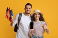 Online Translator App. Happy Young Couple Holding International Flags And Blank Smartphone