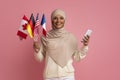 Online Translator App. Smiling Muslim Woman Holding International Flags And Smartphone
